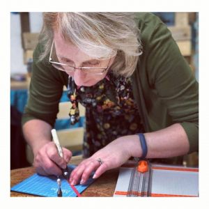 lady bending over and cutting paper with a craft knife