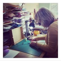 A woman at a workbench using scissors to make paper crafts